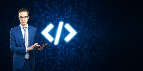 Attractive young european businessman using tablet with glowing programming code on blue binary coding background with mock up place. Program and software development concept.