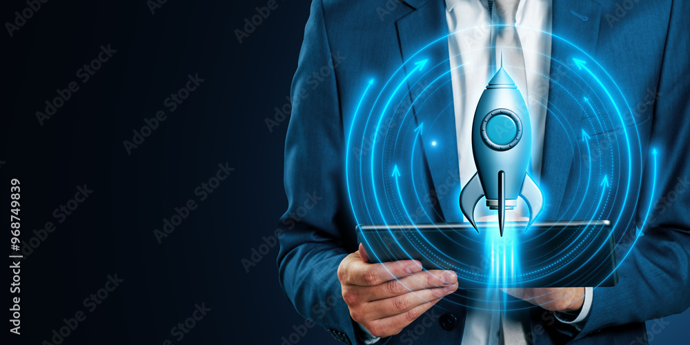 Poster Close up of businessman hands using tablet with glowing rocket on blue background with mock up place. Digital transformation, start up and boost concept.