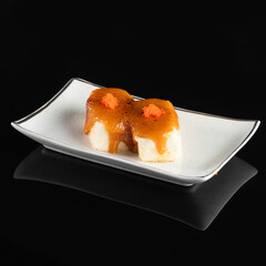 Elegant presentation of gourmet dessert with caramel sauce and fruit topping on white plate against black background.