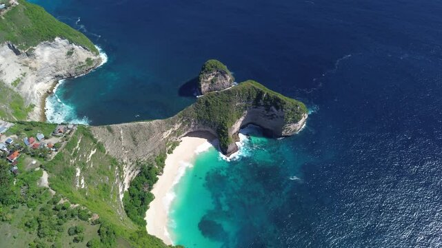 Drone footage capturing a wide aerial orbit of Kelingking Beach in Bali, Indonesia, highlighting the turquoise waters, dramatic cliffs, and the surrounding landscape.