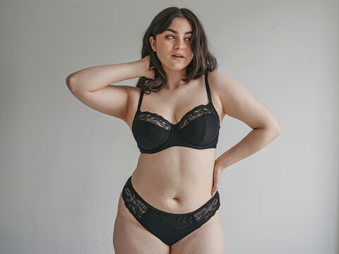 Attractive young woman with a curvy, fuller figure, confidently posing in black lingerie