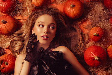 Top view gorgeous stunning lady in aristocrat outfit lying halloween decor pumpkin touch face look...