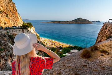 The girl in white hat and red dress watches panoramic  Kaputas Beach, Kas Antalya Turkey