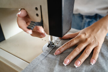 Close up on hands of unknown woman sewing on electric sewing machine
