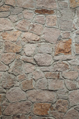 Masonry of the exterior wall made of natural rubble stone, as a background, vertical image, copy space.
