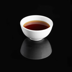 Minimalistic white cup filled with black tea on a black background, showcasing elegance and simplicity in beverage presentation.