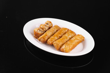 Plate of crispy spring rolls on black background, perfect for food and restaurant themes. Showcasing appetizing Asian snack or appetizer.
