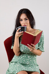 portrait of a beautiful woman with long hair holding a mug and reading a book.