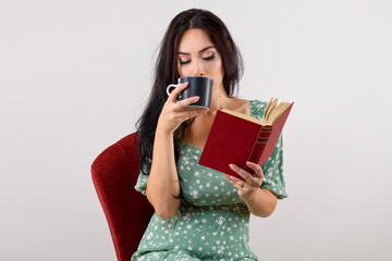 portrait of a beautiful woman with long hair holding a mug and reading a book.