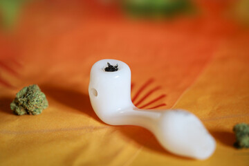 Marijuana glass pipe. Glass pipe or bong for marijuana cannabis smoking on an orange background.