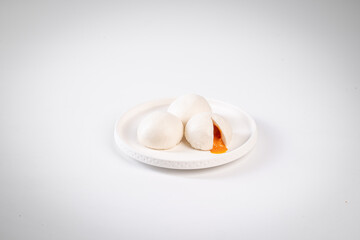Steamed buns filled with custard, placed on a white plate against a plain background, showcasing traditional Asian cuisine.