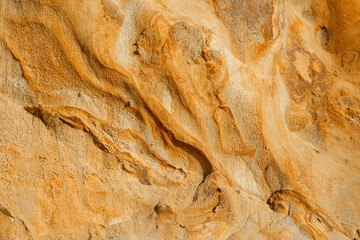 Natural texture background of sandstone rocks with lines, curves, prints in the As Amoeiras and Formosa beach cliffs in Santa Cruz, Portugal.