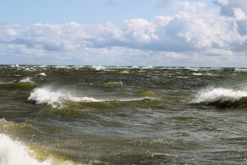 lapping sea waves with white splashes with light blue sky in the background