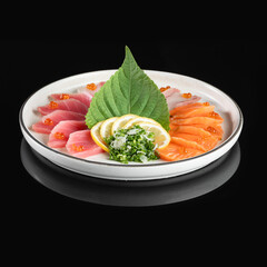 Fresh sashimi assortment with salmon, tuna, and snapper garnished with lemon slices and greens on a white plate.