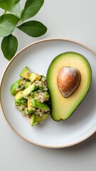Single avocado half with quinoa salad on white plate, minimalist composition.