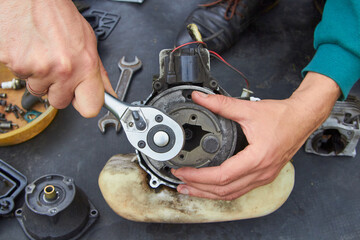 disassemble a broken brush cutter, a man with a key disassembles the clutch in a brush cutter,...