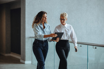 Busy corporate morning: Executive assistant using a tablet to give her boss a briefing on her meetings and appointments.