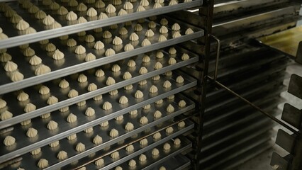 Baking trays getting filled with cookie dough in food factory.