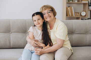 Cheerful cute granddaughter kid and happy grandma hugging with love, tenderness, affection, Grandmother embracing grandchild, enjoying family relationship.