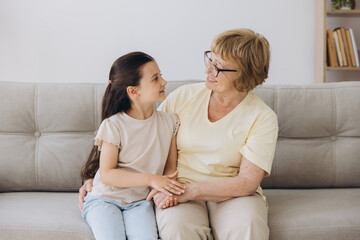 Cheerful cute granddaughter kid and happy grandma hugging with love, tenderness, affection, Grandmother embracing grandchild, enjoying family relationship.