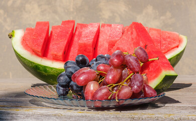 ripe grapes close-up on a plate and red watermelon cut into slices