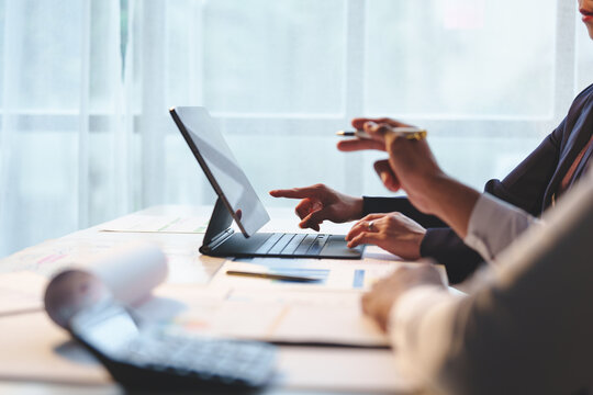 Team of business people pointing at digital tablets and pointing at charts on screen while explaining online marketing information to colleagues. Discussion. Consultation. Collaboration.