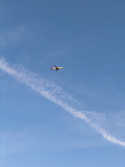 An airplane captured mid-flight against a clear blue sky, leaving a faint contrail behind, symbolizing travel and freedom.