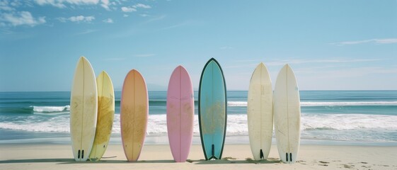 Seven vibrant surfboards stand aligned on the beach, facing the ocean waves, ready for an adventurous day in the surf.