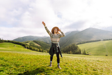 Young traveler woman enjoying the fresh mountain air in a scenic landscape while wearing a hat during the daytime. Travel, nature concept