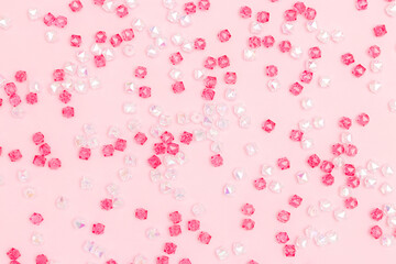 Texture made from different acrylic beads scattered on a pink background.
