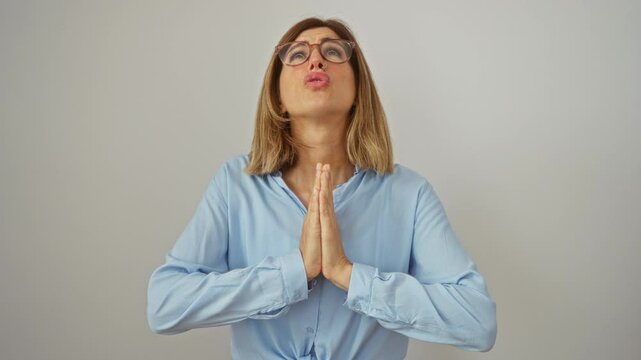 Young blonde woman wearing glasses standing begging and praying with hopeful expression, hands together, over isolated white background, desperately seeking help and forgiveness