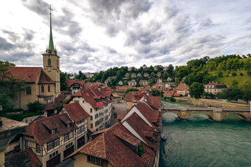 Naklejka premium Charming architecture along the river Aare in Bern, Switzerland under a dramatic cloudy sky