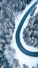 Aerial view of a winding road surrounded by snowy trees, creating a serene winter landscape.