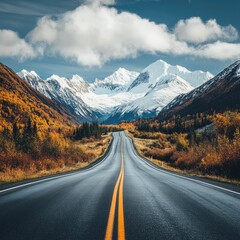 Fototapeta premium A scenic road leads through majestic mountains and vibrant autumn foliage, capturing the essence of nature's beauty.