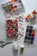 Colorful beads, letter beads, threads and other jewelry making supplies on white background. Making friendship bracelets concept. Flat lay.