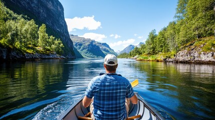 A man in a plaid shirt rows a boat on a tranquil lake surrounded by lush greenery and mountains. Clear blue sky with white clouds reflects on the water's surface.