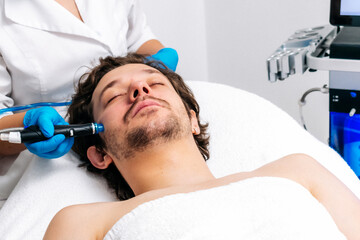 Man undergoing a facial peeling procedure in a beauty clinic, close-up. Rejuvenating hydro-air skin...