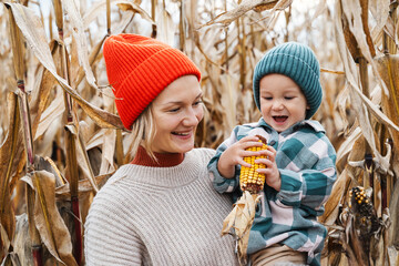 Obraz premium Mother and son exploring corn harvest in background of an agricultural field area.