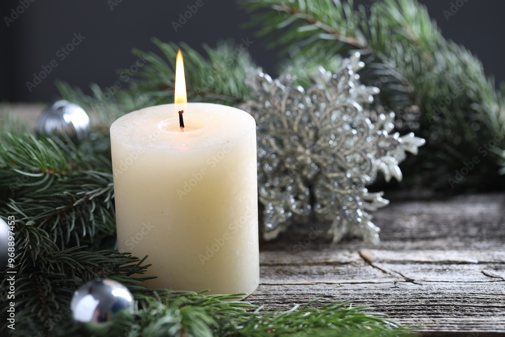 Sticker Burning candle, baubles and fir tree branches on wooden table, closeup. Space for text