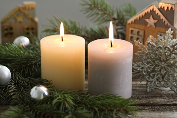 Burning candles, baubles and fir tree branches on wooden table, closeup