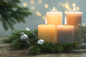 Burning candles, baubles and fir tree branches on wooden table, closeup