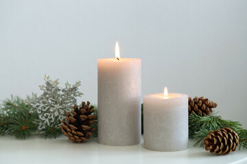 Burning candles and fir branches on white table. Christmas atmosphere