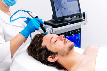 Man undergoing a facial peeling procedure at a beauty clinic. Rejuvenating hydro-air skin cleansing...