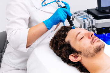 Man receiving a hydrafacial treatment in a modern cosmetic center. Innovative skin hydration and...
