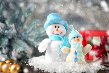 Cute snowmen against blurred background, space for text. Bokeh effect