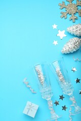 Flat lay composition with confetti and other Christmas decor on light blue background, space for text