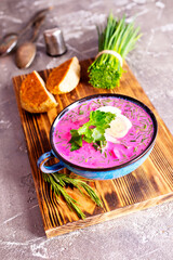 Traditional east european soup. Cold summer soup of beets, kefir, cucumbers, eggs and dill in a blue bowl closeup.