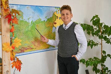A smiling boy is doing his homework at the table. A student uses a microscope. Elementary school.