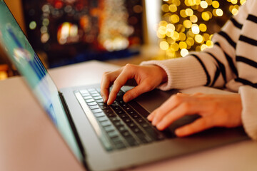 A person typing on a laptop in a cozy setting decorated with warm holiday lights during the festive season. . Business, Freelance, Shopping, education. Online. Cyber security concept