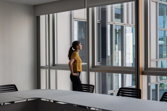 Businesswoman alone in an empty office conference room looking out of the window
